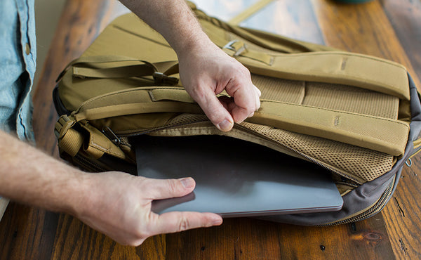 A person putting a laptop into the laptop compartment of the Guide's Edition Synik 30.